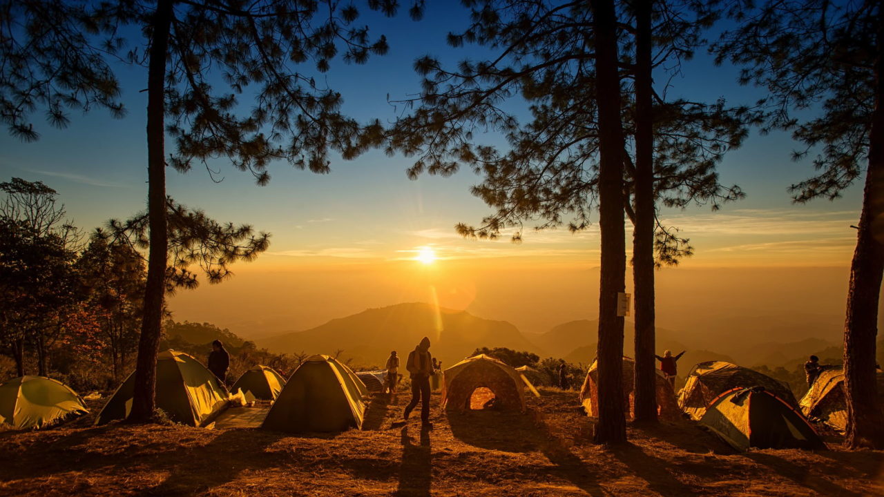 Mehrere Zelte auf einem Berg im Sonnenuntergang