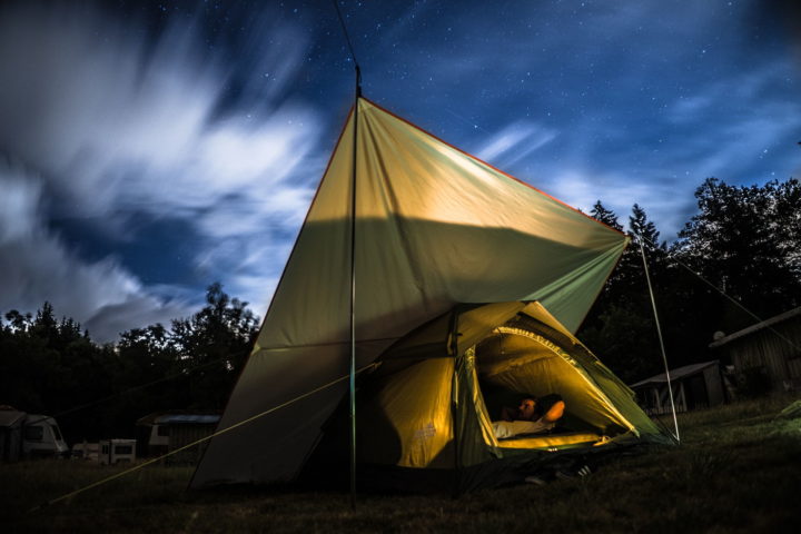 Mann liegt im Zelt unter einem Tarp bei Nacht
