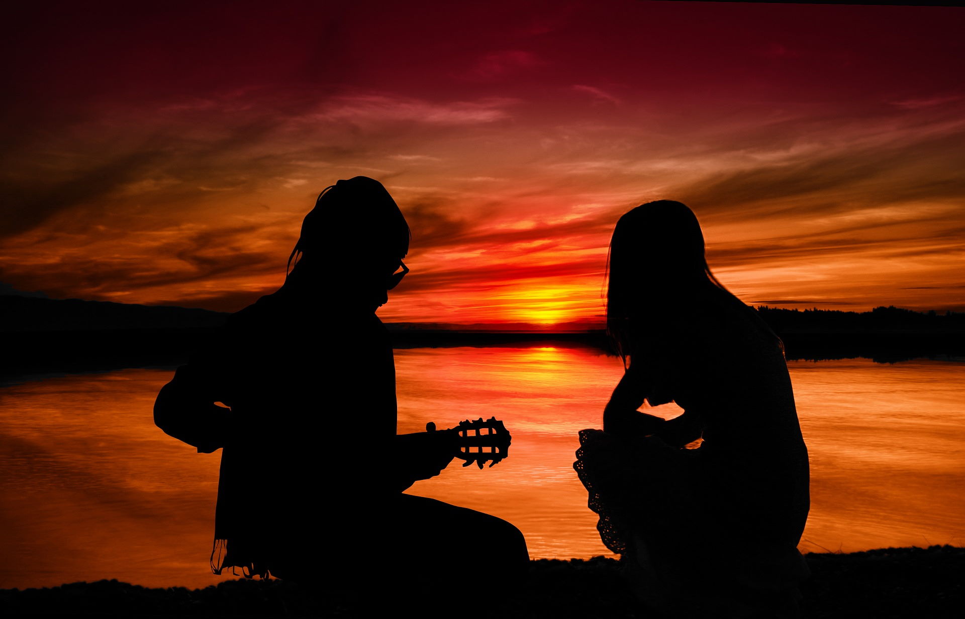 Mann und Frau mit Gitarre im Sonnenuntergang