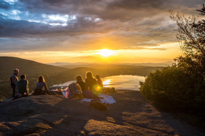 Menschen machen ein Picknick auf einem Berg und schauen auf einen See in den Sonnenuntergang [Camping, Zelten, Outdoor]