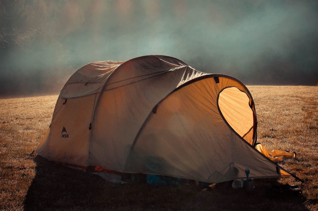 Ein braunes Zelt steht auf einer nebeligen Wiese