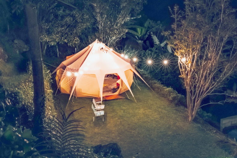 Mit einer Lichterkette beleuchtetes Zelt im Wald bei Nacht