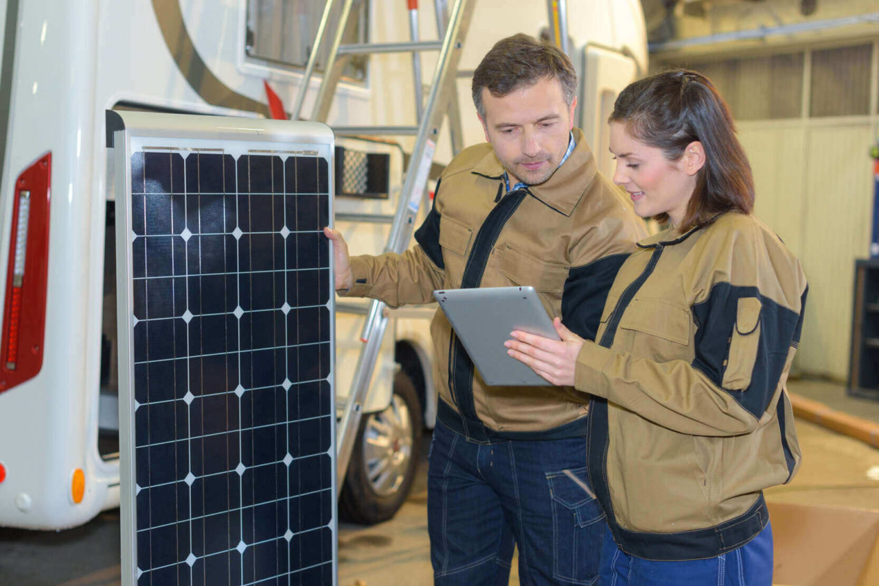 Solarpaneel wird von Frau und Mann auf Reisemobil montiert