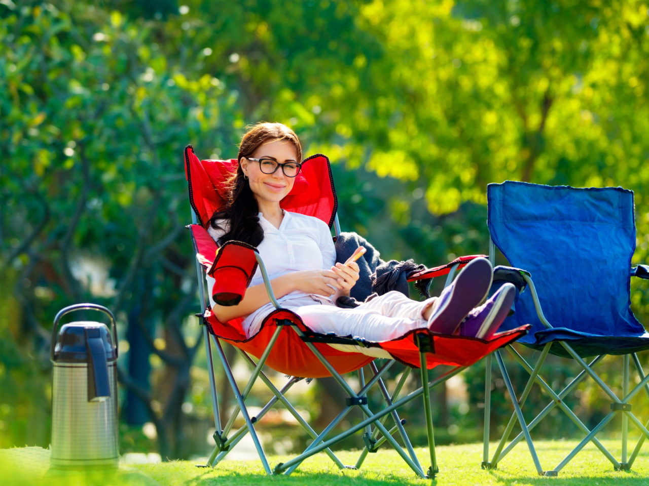 Junge Frau sitzt in einem roten Campingstuhl