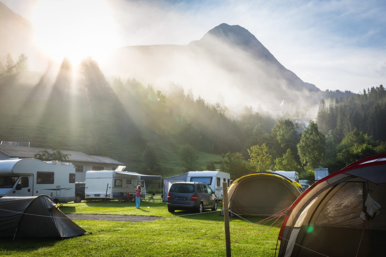 Campingplatz mit Zelten, Stellplatz mit Wohnmobilen, Sonnenstrahlen im Sonnenaufgang