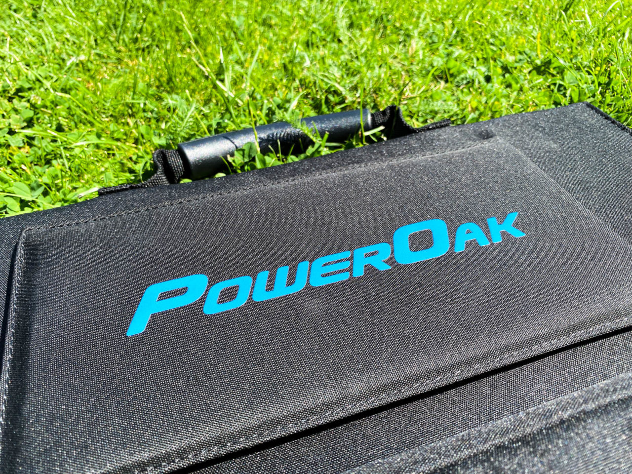 PowerOak Bluetti SP120 Solarpanel Test - Nahaufnahme der Solartasche im Gras, PowerOak Logo
