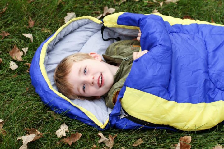 Kind in Mumienschlafsack auf der Wiese
