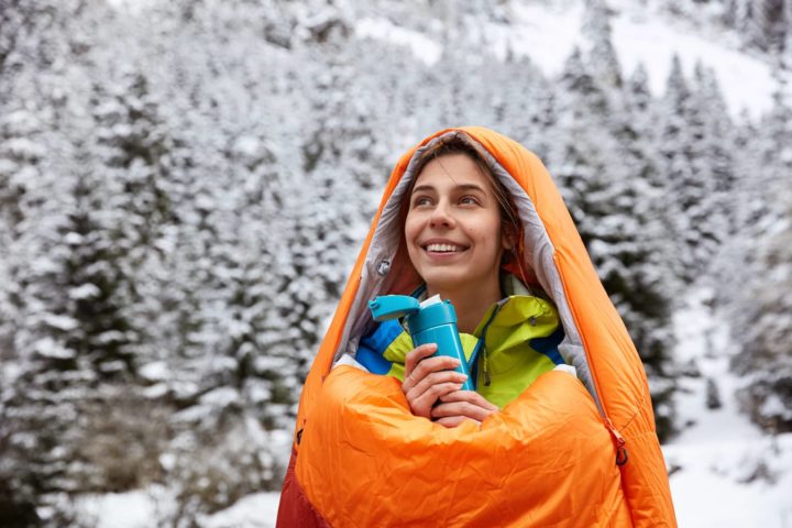 Frau im Schlafsack bei Schnee